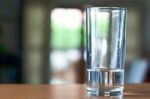 Glass Of Water On A Wooden Desk And Living Room Background Stock Photo