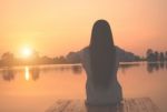 Silhouette Of Relaxing Young Woman On Wooden Pier At The Lake In Sunset Stock Photo