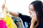 Young Woman Talking On The Phone While Shopping For Clothes Stock Photo