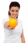 Smiling Lady Offering You An Orange Stock Photo