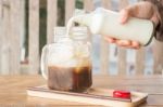 Pouring Milk To Iced Glass Of Coffee Stock Photo