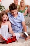 Kids Opening Christmas Gifts With Parents In The Background Stock Photo