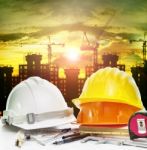 Safety Helmet On Engineer Working Table And Construction Site Background Stock Photo