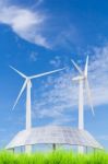 Solar Panels And Wind Turbine On Green Grass Field Against Blue Stock Photo