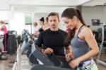 Happy Coach Assisting Young Woman In A Gym Stock Photo