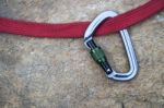 Image Of A Carabiner Hook And Red Rope On Rock Background Stock Photo