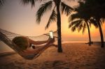 Woman Lying In Beach Cradle And Taking A Photograph By Smart Phone Stock Photo