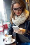 Beautiful Girl Using Her Mobile Phone In Cafe Stock Photo