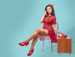 Happy Young Pinup Woman Sitting On A Chair And Talking On Phone Stock Photo