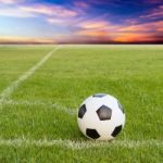 Soccer Ball On Soccer Field Against Sunset Sky Stock Photo