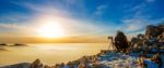 Professional Photographer Takes Photos With Camera On Tripod On Rocky Peak At Sunset Stock Photo