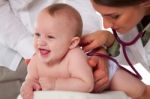 Doctor Listening To Toddler's Back With Stethoscope Stock Photo