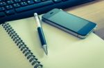 Pen And Cell Phone On A Notebook With Keyboard Stock Photo