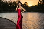 Beautiful Young Woman In The Gardens Wearing A Long Silk Red Dress Stock Photo