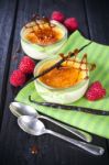 The Creme Brulee In Glass Dish With Vanilla Pods And Raspberries Stock Photo