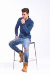 Male Model In Denim Jeans Sitting On A Chair . Studio Shoot Stock Photo