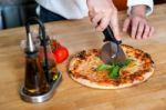 Chef Cutting Pizza Into Pieces Stock Photo