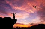 Silhouette Of A Man On The Rock And Silhouette Commercial Plane Stock Photo