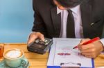 Business Man Sitting On A Calculator To Figure Out In A Coffee S Stock Photo