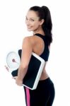 Female Fitness Trainer Holding Weighing Machine Stock Photo