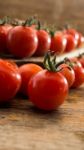 Cherry Tomatoes On Display On Wooden Chopping Board And Wooden Table Stock Photo