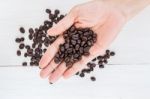 Coffee Beans In Hand Against Coffee Background Stock Photo