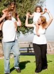 Parents Holding Children On Shoulder Stock Photo