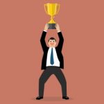 Businessman Holding Up A Winning Trophy Stock Photo