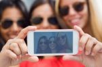 Three Friends Taking Photos With A Smartphone Stock Photo