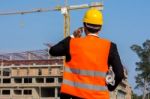 Young Engineer Wearing A Orange Shirt Stands Holding A Blueprint Stock Photo