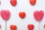 Pink Valentine's Day Heart Shape Lollipop With Small Red Candy In Cute Pattern On Empty White Paper Background. Love Concept. Colorful Hipster Style. Knolling Top View Stock Photo