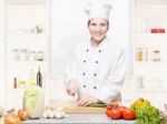 Female Chef Cutting Onions On The Cutting Board In Kitchen Stock Photo