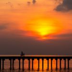 Silhouette Boy Ride Bicycle On The Bridge At Sunset Stock Photo