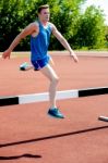 Male Athlete Jumping Hurdle Stock Photo