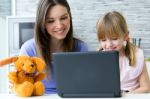 Mother And Daughter Using Laptop In The Kitchen Stock Photo