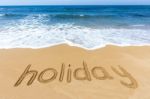 Word Holiday Written In Sand On Beach Stock Photo