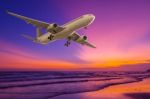 Commercial Airplane Flying Above The Sea At Sunset Stock Photo