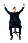 Smiling Man Sitting And Arms Raised Stock Photo