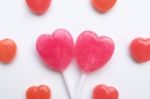 Pink Valentine's Day Heart Shape Lollipop With Small Red Candy In Cute Pattern On Empty White Paper Background. Love Concept. Colorful Hipster Style. Knolling Top View Stock Photo