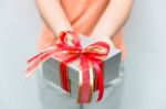 Hand Give Silver Gift Box With Red Ribbon Stock Photo