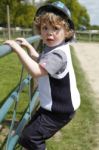 Young Boy With Hat On Climbing On A Gate Stock Photo