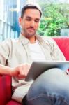 Young Man Using Digital Tablet On Sofa Stock Photo