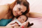 Happy Mum And Baby Boy Smiling In The Bed Holding Teddy Bear Stock Photo