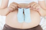 Pregnant Belly With A Pair Of Blue Socks Stock Photo