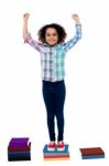 Excited Pretty School Child Standing On Books Stock Photo