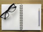 White Paper Note Book With Grey Pencil And Black Glasses In Angl Stock Photo