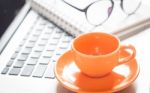 Laptop With Coffee Cup And Notepad On Desk Stock Photo