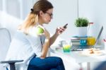 Pretty Young Woman Eating An Apple And Working At Home Stock Photo