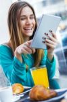 Pretty Woman Using Tablet While Having Breakfast In Coffee Shop Stock Photo