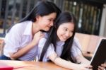 Two Asia Thai High School Student Uniform Best Friends Beautiful Girl Using Her Tablet And Funny Stock Photo